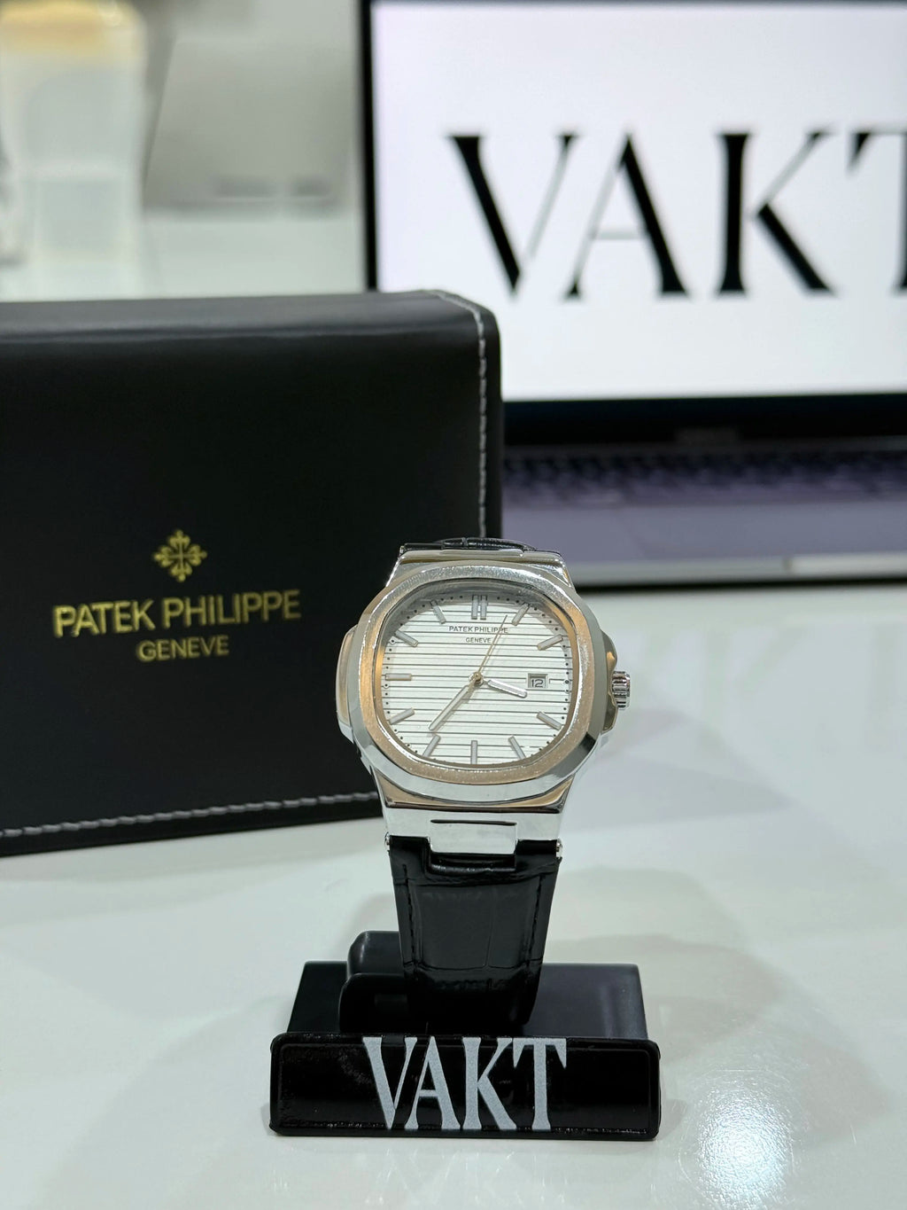 Patek Philippe whitte dial watch on a stand with 'Vakt' branding in the background