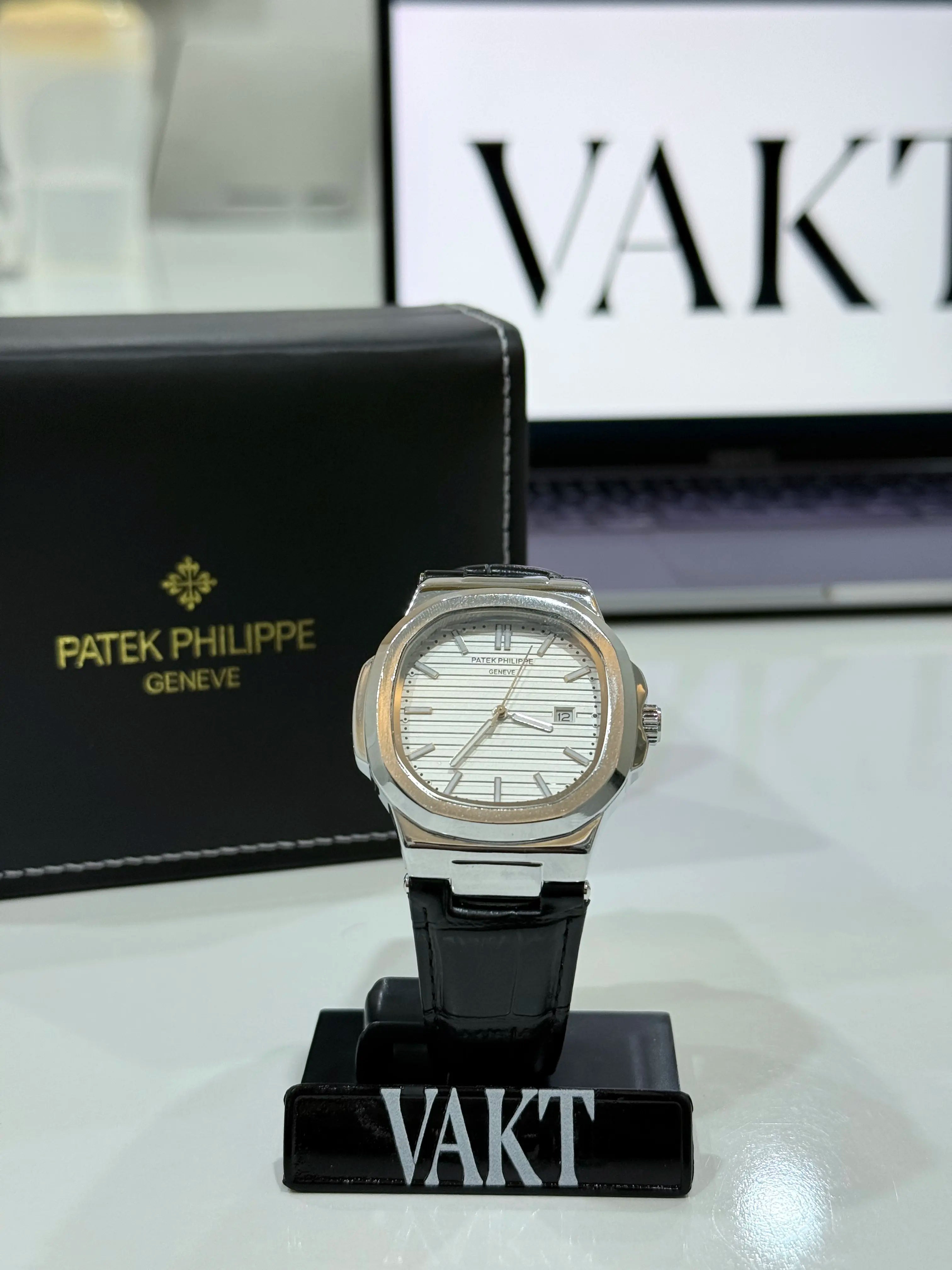 Patek Philippe whitte dial watch on a stand with 'Vakt' branding in the background