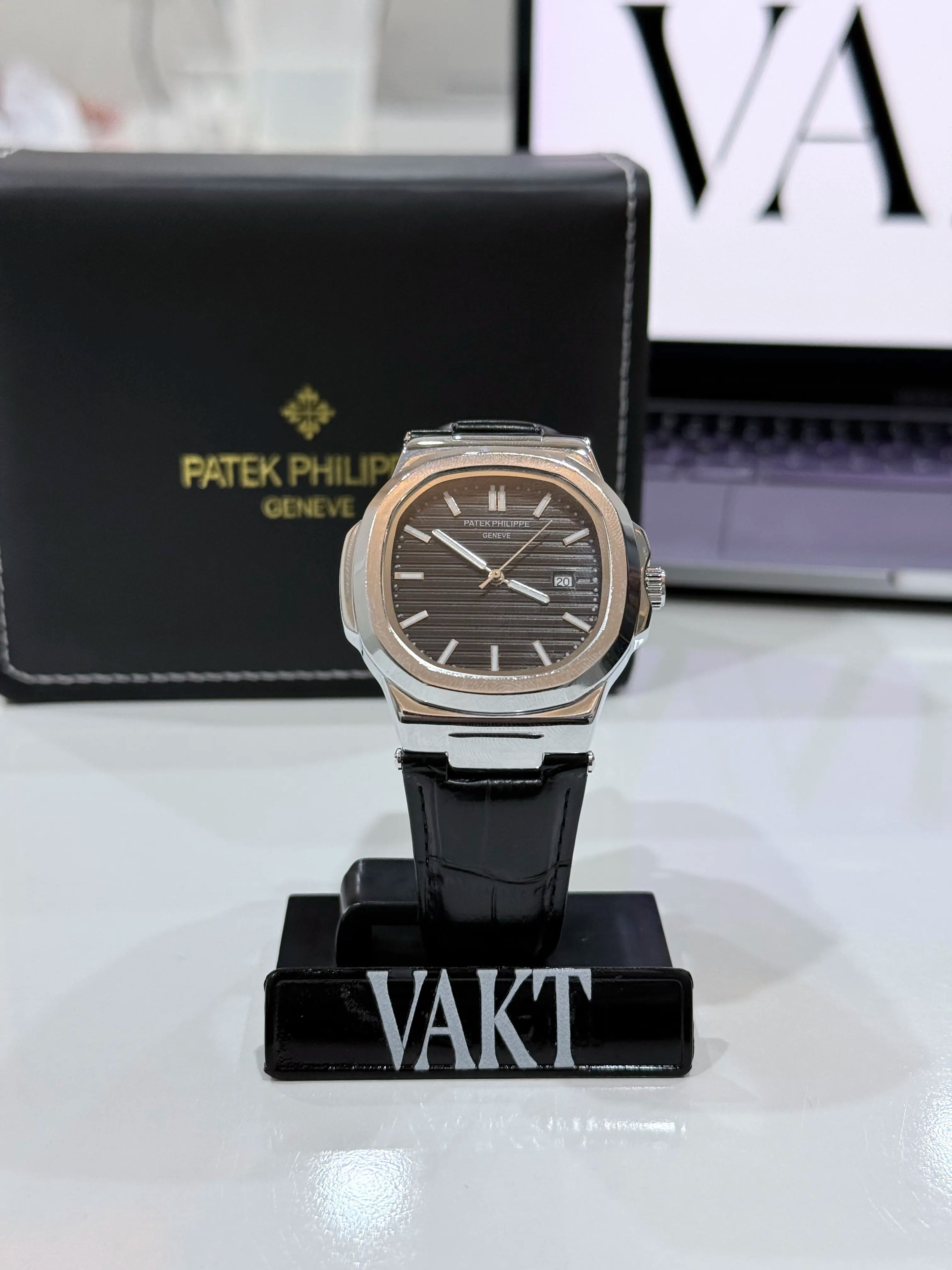 Luxury watch on a stand with Patek Philippe branding in the background