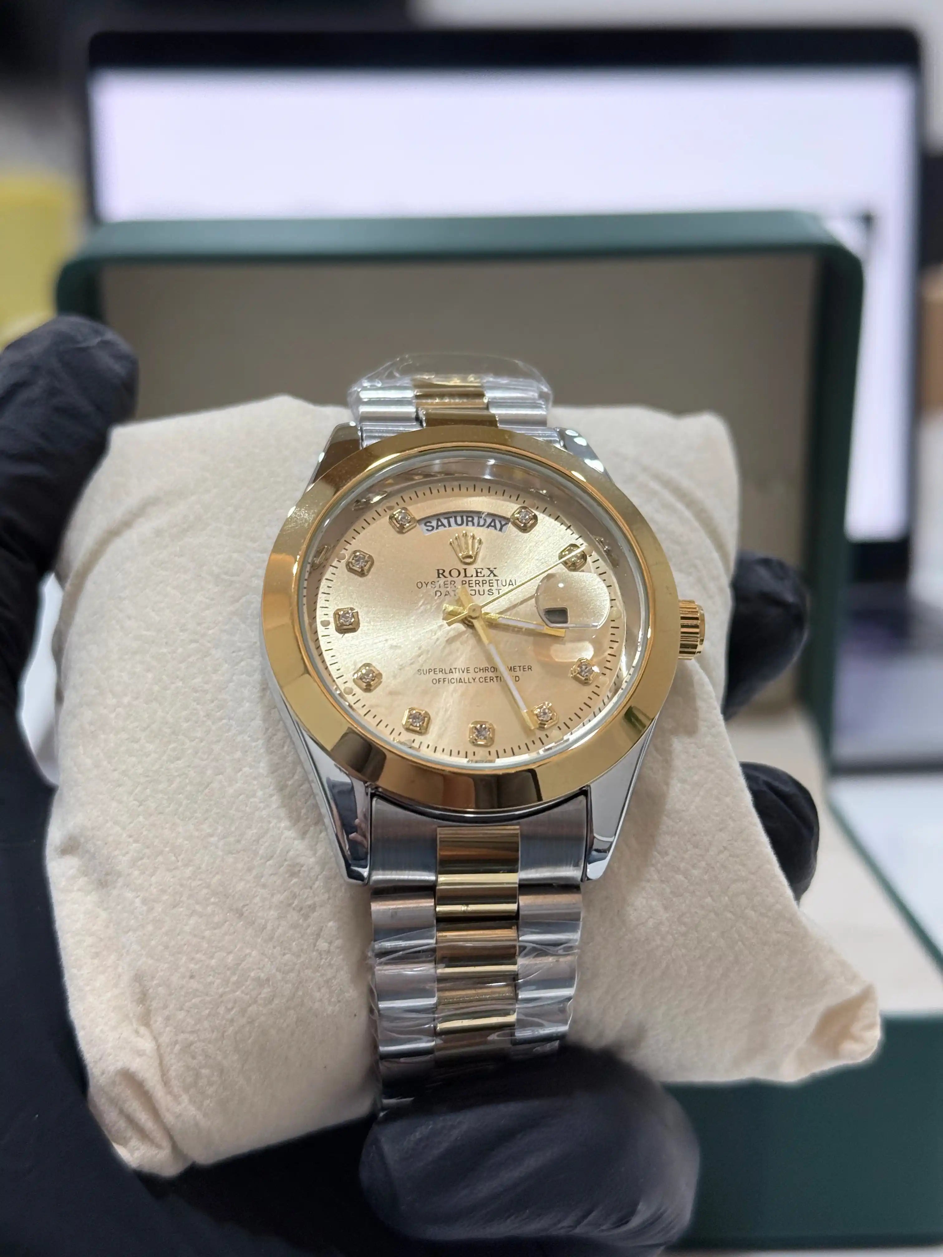 Gold and silver rolex oyster perpetual day-date watch on a white cloth with a blurred background