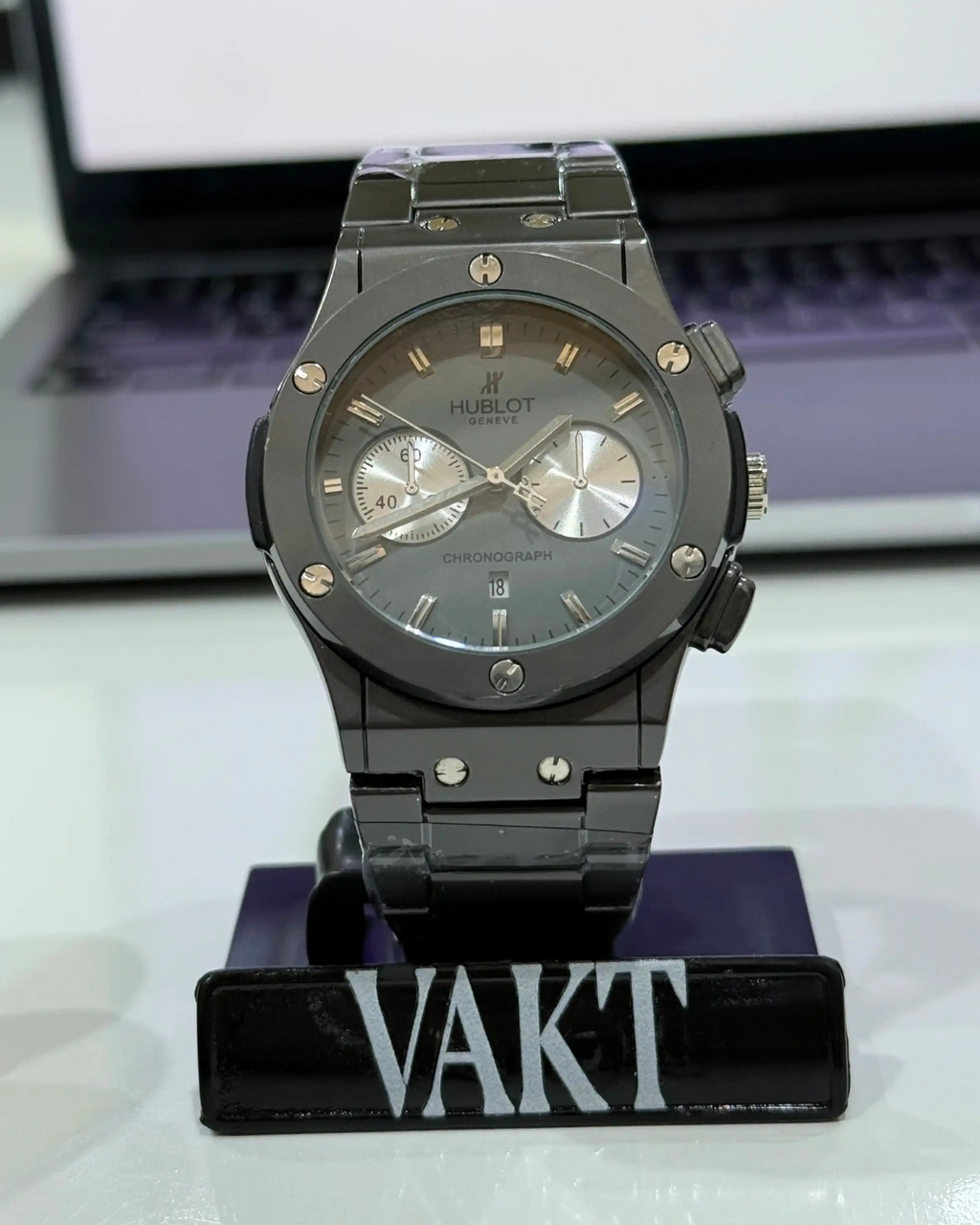 Black Hublot watch on a stand with a blurred background