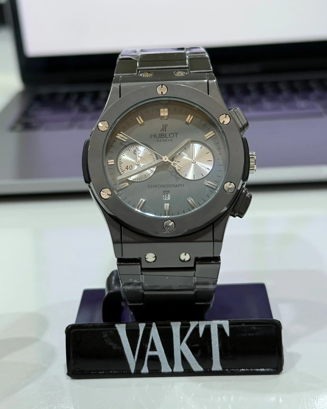 Black Hublot watch on a stand with a blurred background